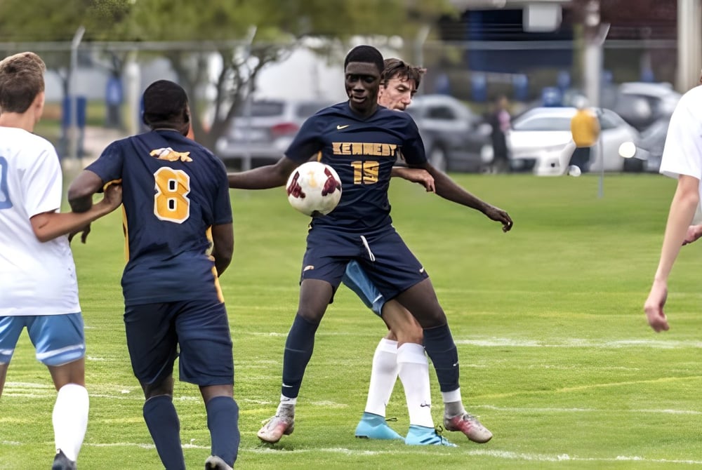 Eine Gruppe Schüler spielt Fußball auf einem Rasenfeld auf dem Gelände der John F. Kennedy High School.