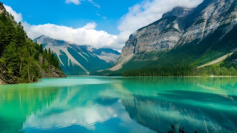 Ein ruhiger türkisfarbener See mit schneebedeckten Bergen und immergrünen Wäldern in der Nähe der John F. Kennedy High School.