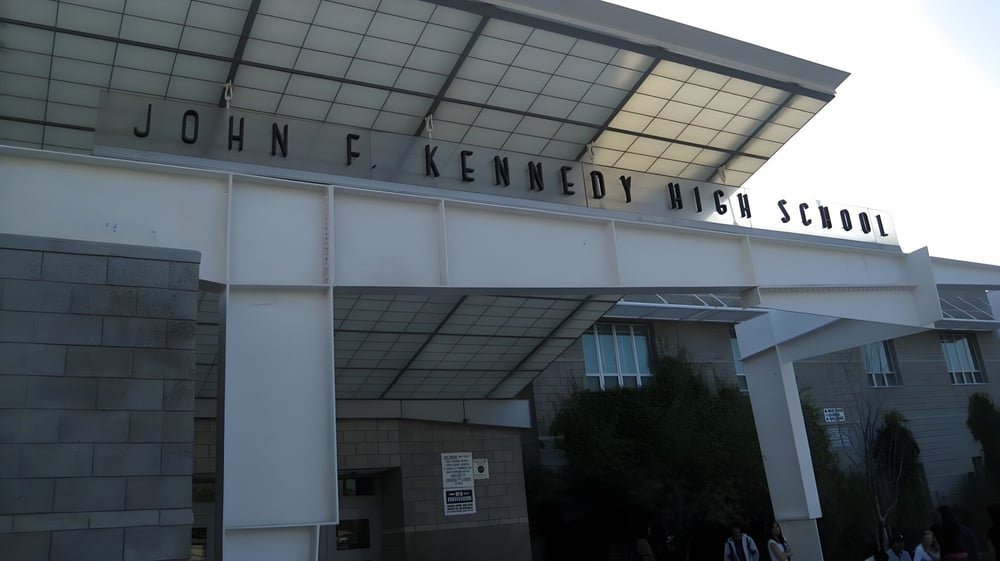Das moderne Hauptgebäude der John F. Kennedy High School mit dem Schriftzug an der Fassade.