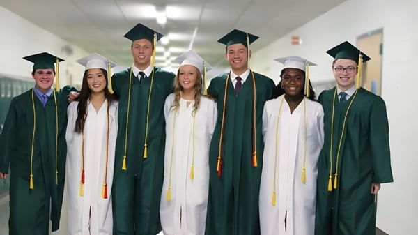 Eine Gruppe Absolventen in grün-weißen Talaren steht im Flur des John F. Ross Collegiate Vocational Institute.