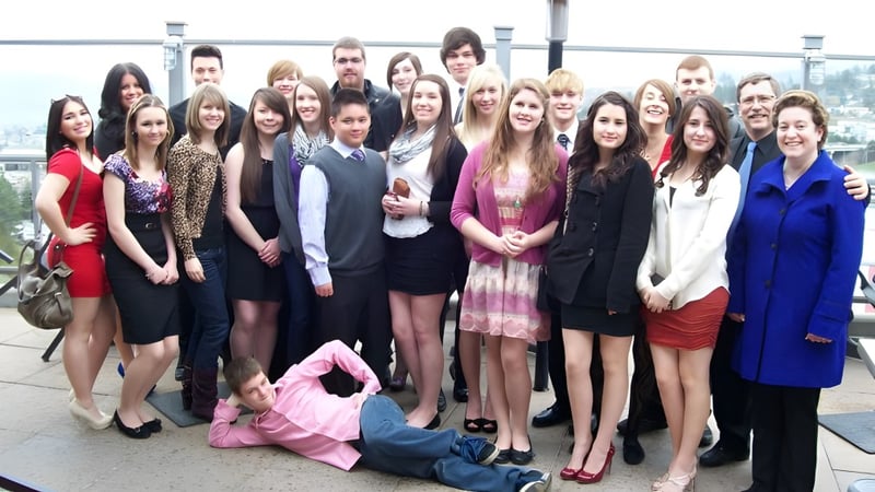 Eine Gruppe Schülerinnen der John Maland High School steht im Freien vor einer Stadtlandschaft.