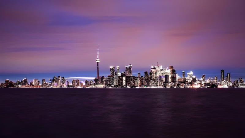 Blick auf die Skyline der Stadt mit dem CN Tower im Sonnenuntergang hinter dem Campus der John McGregor Secondary School.
