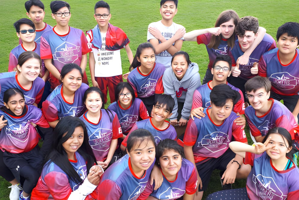 Schüler der John Oliver Secondary School posieren gemeinsam im Sportteam auf einem Fußballfeld.