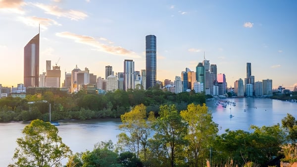 Blick auf eine lebendige Stadt mit Wolkenkratzern und Grünflächen bei Sonnenuntergang nahe dem John Paul College.