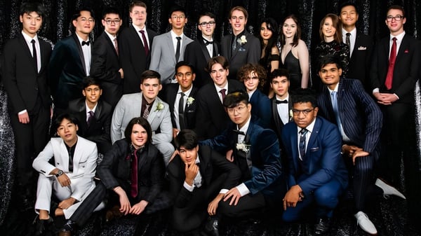 Eine große Gruppe formell gekleideter Schülerinnen und Schüler posiert für ein Gruppenfoto am John Paul College.