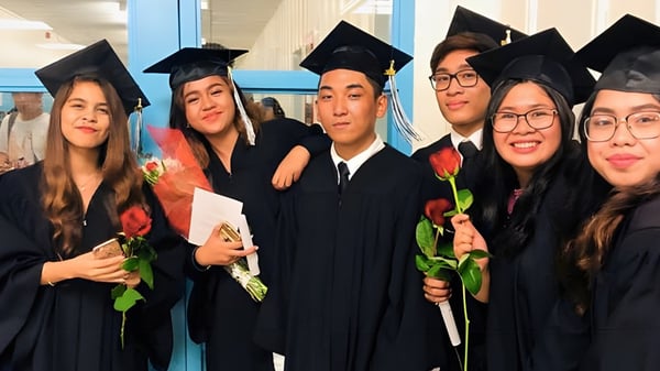 Eine Gruppe von Absolventen in Abschlusskleidung posiert mit Blumen auf dem Campus des John Polanyi Collegiate Institute.