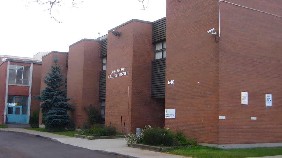 Das mehrstöckige Backsteingebäude mit Baum und Grünfläche auf dem Gelände des John Polanyi Collegiate Institute.