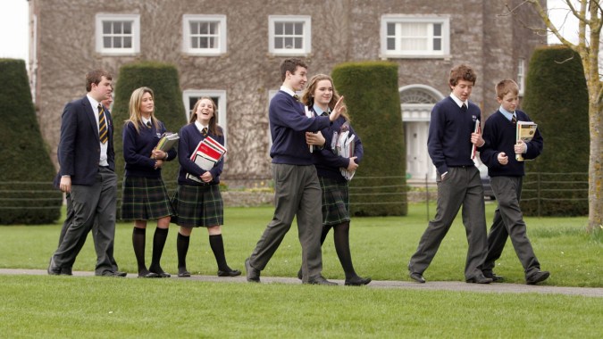 Eine Gruppe Schülerinnen und Schüler der John Scottus Secondary School steht auf einer Grünfläche vor einem großen Gebäude.