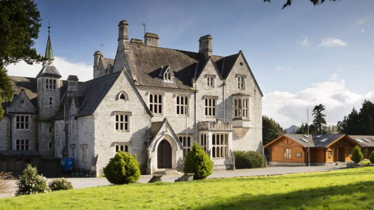 Das historische schlossartige Gebäude auf dem Campus der John Scottus Secondary School ist von grünen Bäumen umgeben.