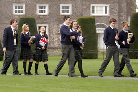 Eine Gruppe Schüler der John Scottus Secondary School steht auf dem Gras vor einem Backsteingebäude.