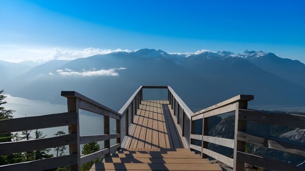 Ein Holzsteg führt in Richtung einer Bergkette unter blauem Himmel auf dem Gelände der Johnston Heights Secondary School.