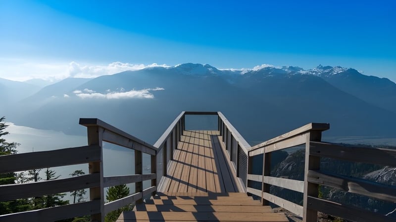 Ein Holzsteg führt in Richtung einer Bergkette unter blauem Himmel auf dem Gelände der Johnston Heights Secondary School.