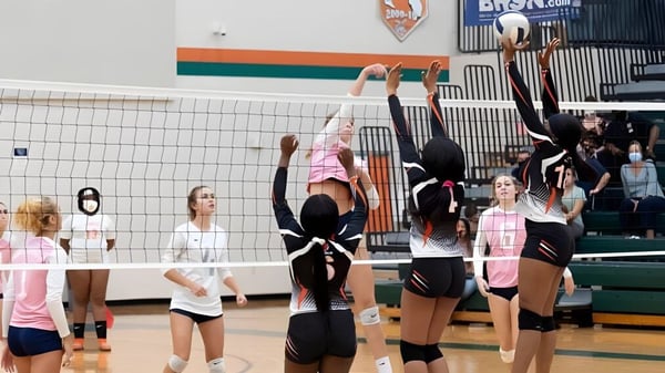 Eine Gruppe von Volleyballspielerinnen der Jones High School tritt in einem Wettkampf auf dem Spielfeld an.