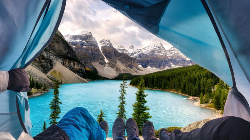 Blick durch das geöffnete Zelt auf einen türkisfarbenen See und schneebedeckte Berge bei der J.T. Foster High School.
