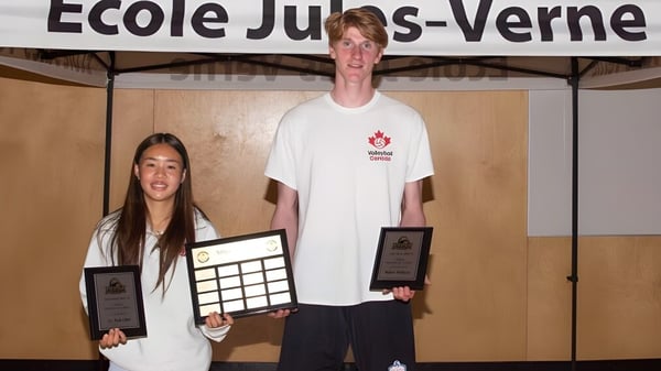 Zwei Schülerinnen und Schüler der Jules Verne school Vancouver halten Auszeichnungen vor dem Schulgebäude.