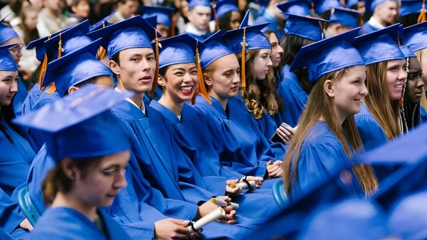 Eine große Gruppe von Absolventen der Jules Verne school Vancouver trägt blaue Abschlusskleidung und steht zusammen.