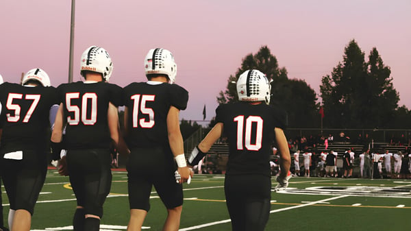Eine Gruppe von Football-Spielern der Justin Siena High School steht auf dem Spielfeld bei Sonnenuntergang.