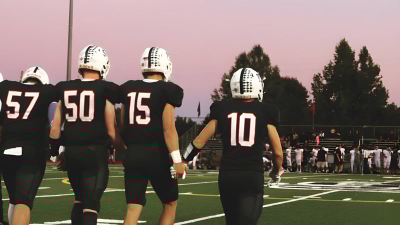 Eine Gruppe von Football-Spielern der Justin Siena High School steht auf dem Spielfeld bei Sonnenuntergang.