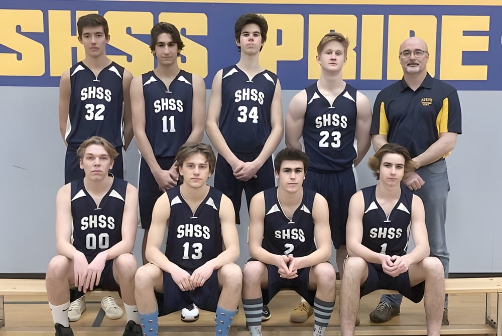 Schülerinnen und Schüler der J.V. Humphries Secondary School posieren gemeinsam in ihren Basketball-Trikots vor blau-gelbem Hintergrund.
