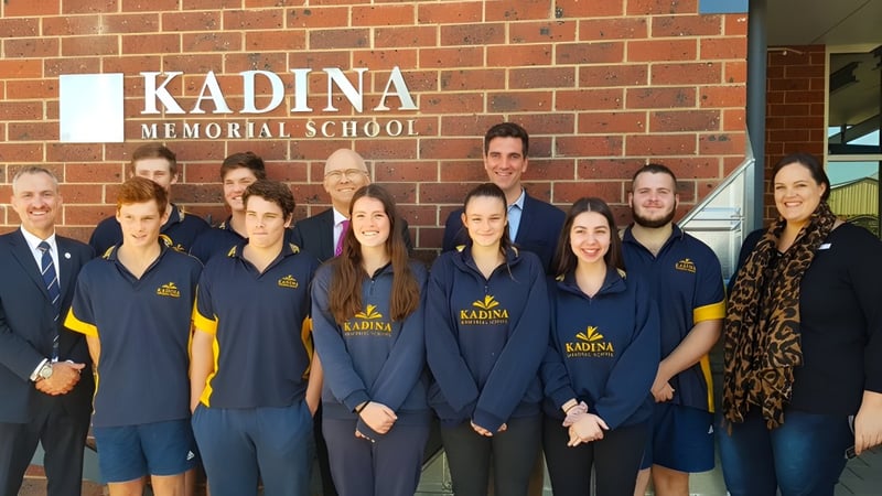 Schüler und Mitarbeiter der Kadina Memorial School posieren vor dem Schulgebäude in blauen Uniformen mit Schullogo.