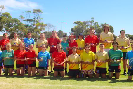 Eine Gruppe Schüler der Kadina Memorial School steht auf dem Sportfeld auf einer Wiese vor Bäumen unter klarem Himmel.