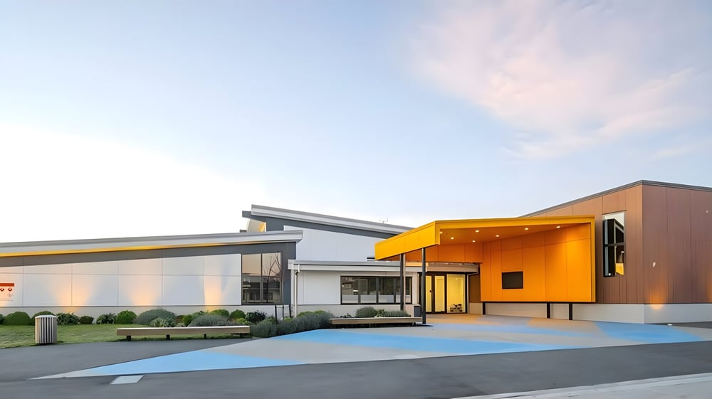 Das moderne, farbenfrohe Gebäude der Kaiapoi High School steht vor klarem Himmel und ist von Wegen und Bepflanzung umgeben.