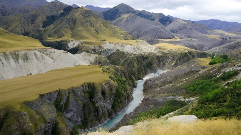 Im Hintergrund sind schneebedeckte Berge zu sehen, vor denen ein Fluss durch das felsige Gelände auf dem Gelände der Kaiapoi High School verläuft.