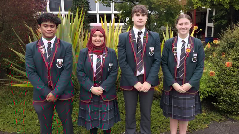 Eine Gruppe von Schülerinnen und Schülern des Kaikorai Valley College steht vor einem Gebäude mit viel Grün im Hintergrund.