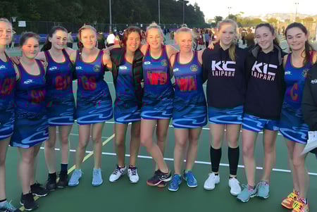 Schülerinnen des Kaipara College stehen in einheitlichen Sportoutfits auf dem Sportplatz und posieren gemeinsam.