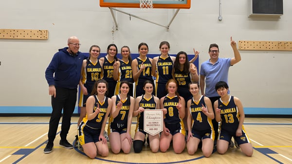Eine Gruppe junger Basketballspielerinnen posiert gemeinsam auf dem Spielfeld der Kalamalka Secondary School.