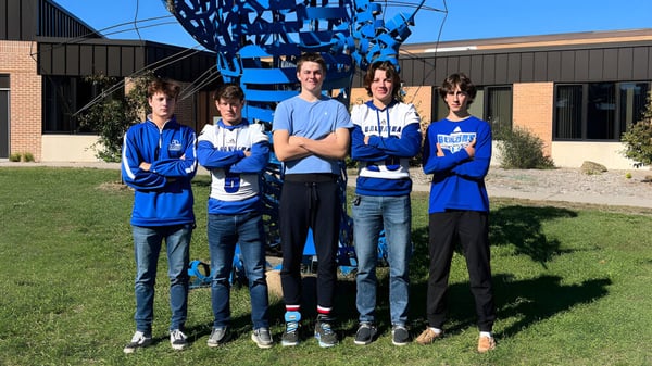 Eine Gruppe von fünf Schülerinnen und Schülern der Kalkaska High School steht vor einer großen blauen und weißen Skulptur auf einem Rasen.