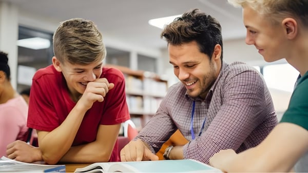 Drei Schüler der Kamloops School of the Arts sitzen gemeinsam am Tisch und diskutieren in einer Lernumgebung.