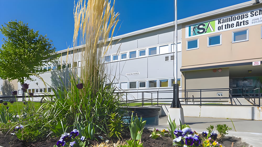 Das moderne Schulgebäude der Kamloops School of the Arts ist mit Pflanzen und Blumen umgeben.