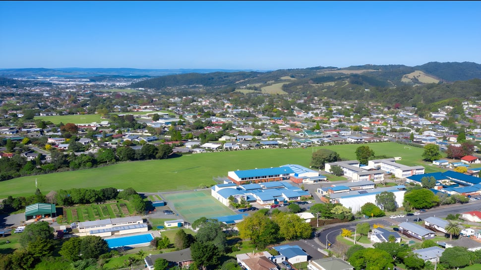 Eine malerische Landschaft mit bunten Häusern und grünen Feldern in der Nähe der Kamo High School.