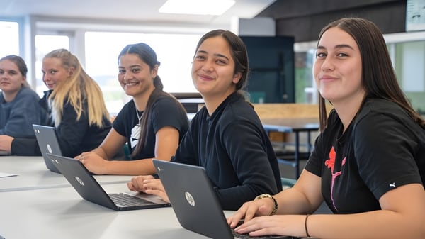 Eine Gruppe von Schülerinnen der Kamo High School arbeitet konzentriert an Laptops in einem modernen Klassenraum.