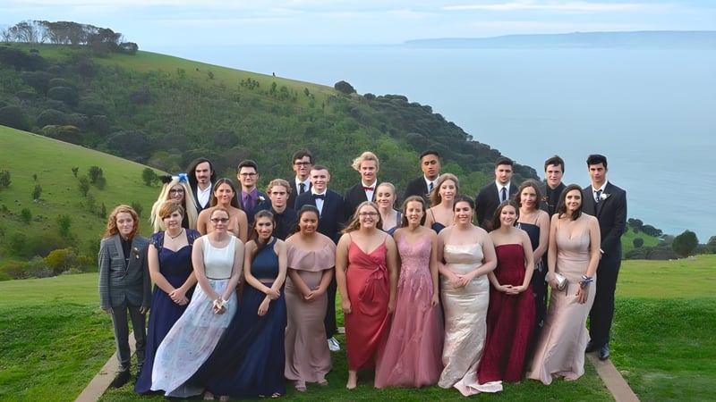 Eine Gruppe von Menschen in formeller Kleidung steht auf einem Weg vor grünen Hügeln auf dem Gelände der Kangaroo Island Community Education.