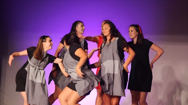 Vier Schülerinnen des Kapiti College stehen gemeinsam auf einer Bühne vor einem violetten Hintergrund.