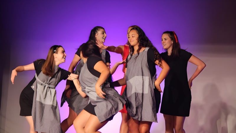 Vier Schülerinnen des Kapiti College stehen gemeinsam auf einer Bühne vor einem violetten Hintergrund.
