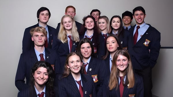 Eine Gruppe Schüler des Kapiti College posiert gemeinsam in Schuluniform vor einem einfarbigen Hintergrund.