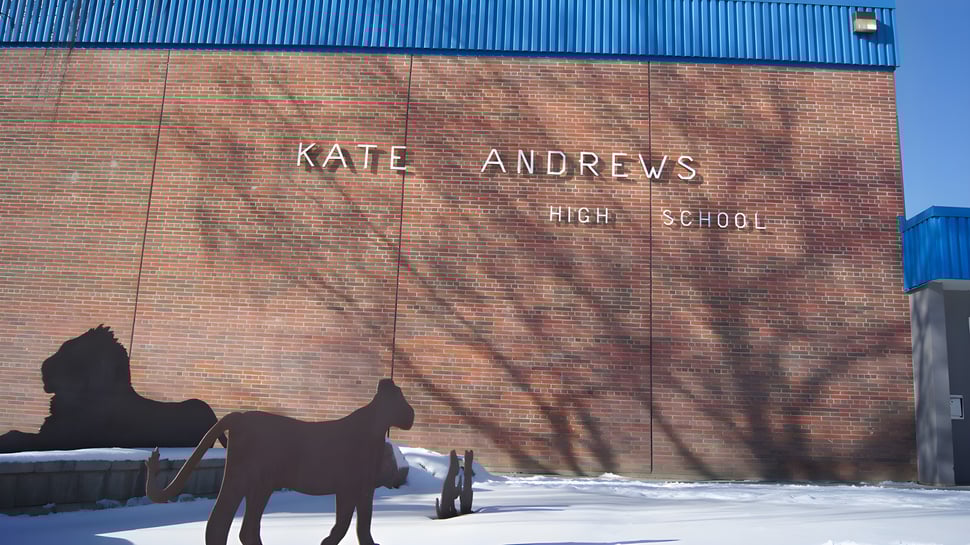 Das Backsteingebäude der Kate Andrews High School mit einer Pferdesilhouette vor verschneitem Hintergrund.