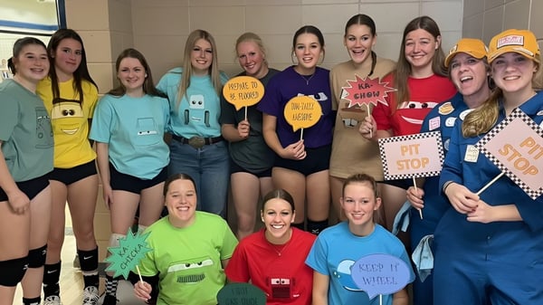 Eine Gruppe von Schülerinnen der Kate Andrews High School hält bunte Schilder mit humorvollen und ermutigenden Botschaften.