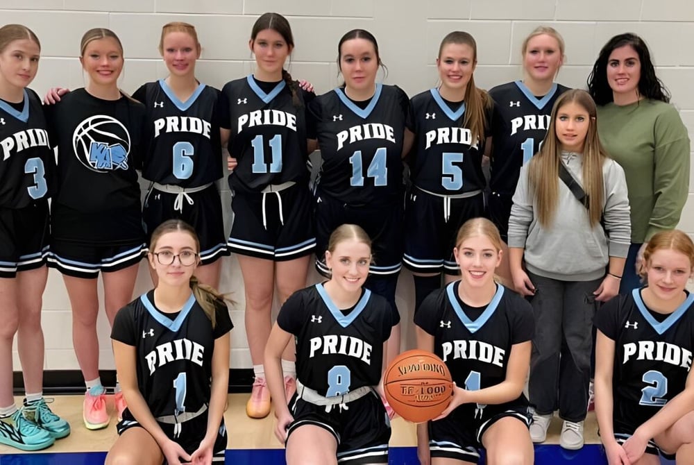 Eine Gruppe junger Basketballspielerin steht zusammen in der Sporthalle der Kate Andrews High School.