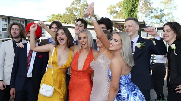 Eine Gruppe Schüler der Kedron State High School feiert gemeinsam vor Schulgebäuden und Bäumen.