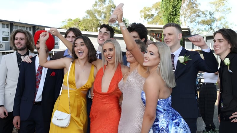 Eine Gruppe Schüler der Kedron State High School feiert gemeinsam vor Schulgebäuden und Bäumen.