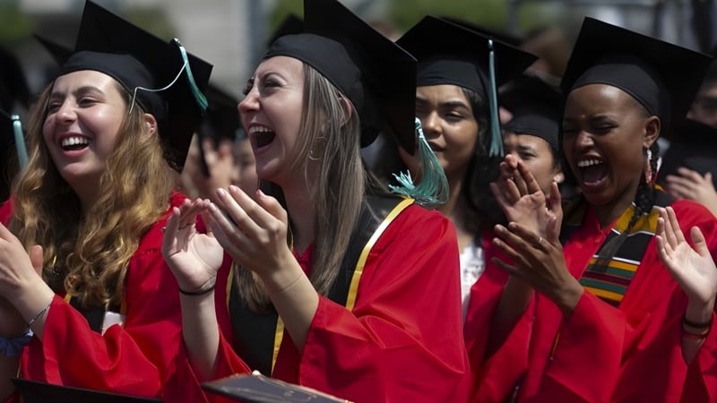 Eine Gruppe von Absolventen in roten Talaren und Baretten feiert ihren Abschluss an der Keebra Park State High School.