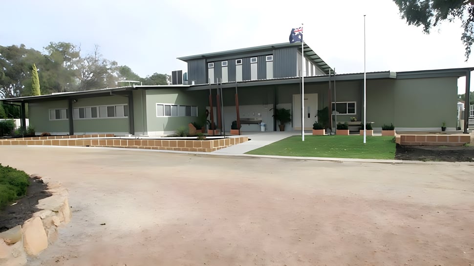 Das moderne eingeschossige Schulgebäude der Kelmscott Senior High School ist von Bäumen und Grünflächen umgeben.