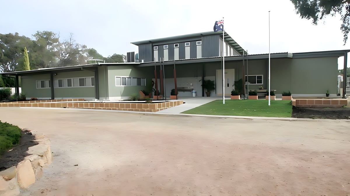 Das moderne eingeschossige Schulgebäude der Kelmscott Senior High School ist von Bäumen und Grünflächen umgeben.