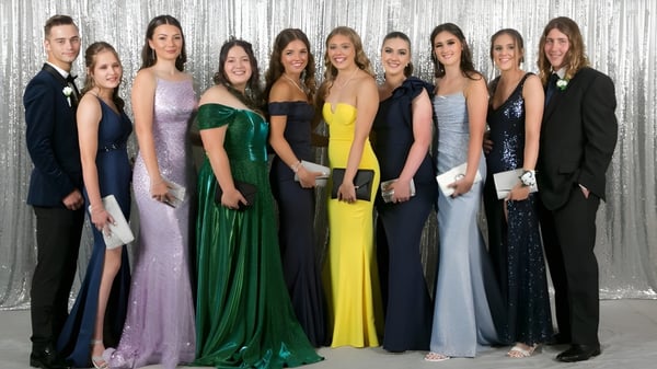 Eine Gruppe elegant gekleideter Personen posiert vor einem silbernen Hintergrund auf dem Campus der Kelmscott Senior High School.