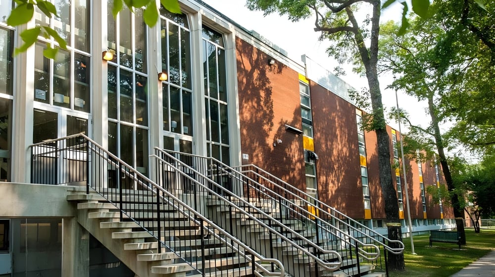 Das mehrstöckige Backsteingebäude der Kelvin High School ist von Bäumen und einer Rasenfläche umgeben.