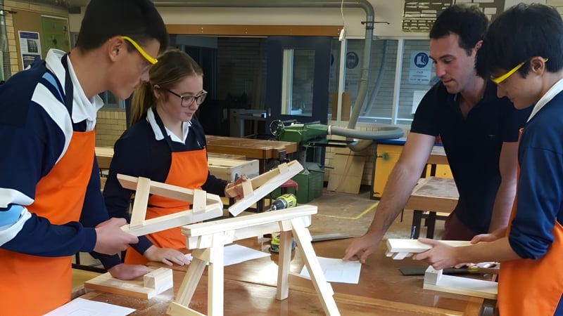 Schüler der Kelvin High School arbeiten gemeinsam an einem Holzprojekt in der Werkstatt.